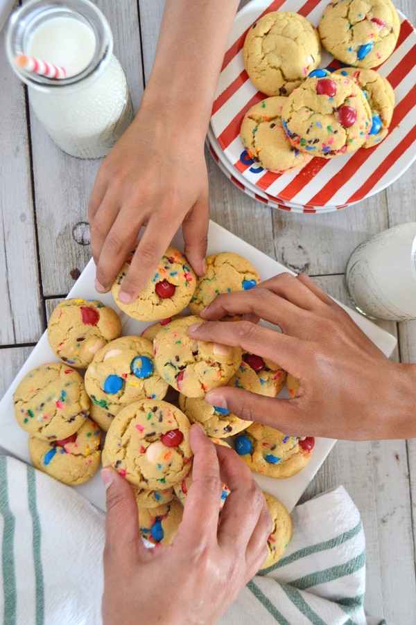 Hands reaching out to grap fireworks pudding cookies to eat with a glass of milk