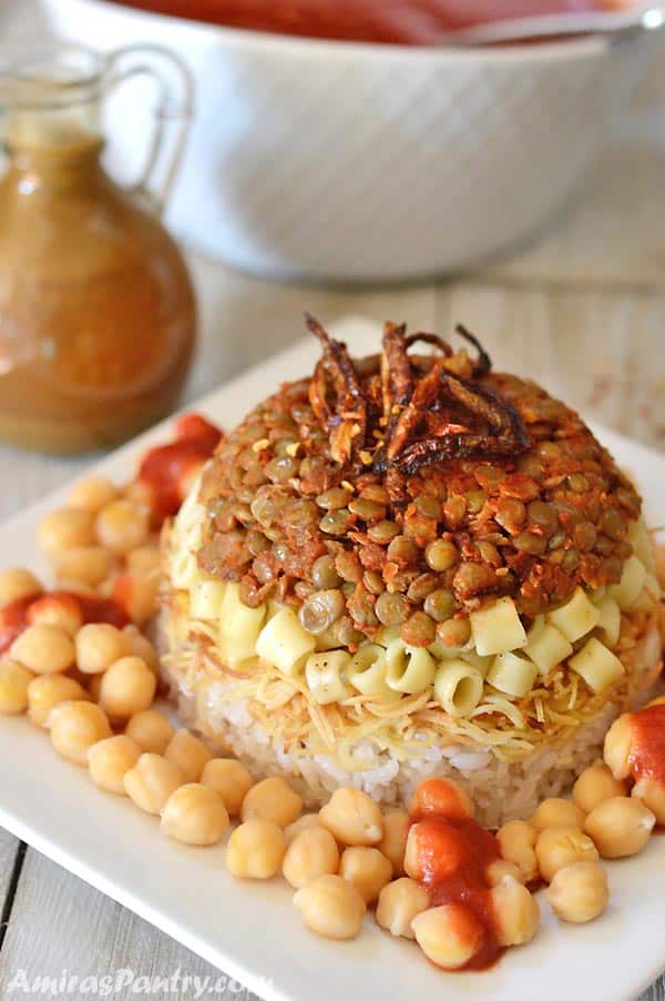 A plate of Egyptian koshary topped with crunchy fried onions and chickpeas all around.