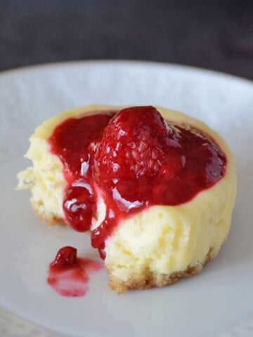 A close up of cupcake on a plate, with Cream cheese and raspberry