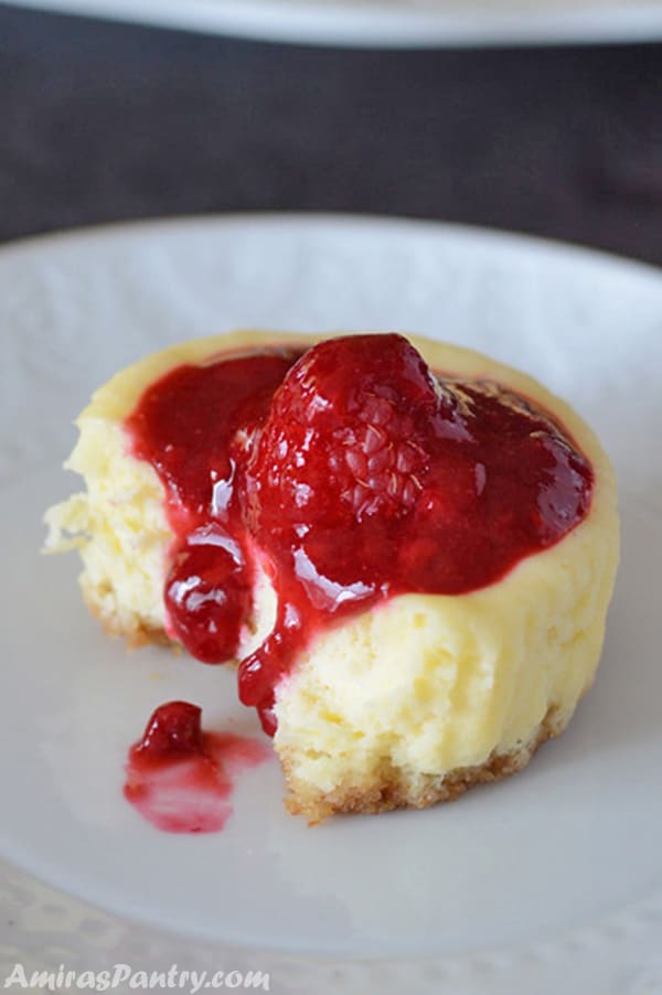 A close up of cupcake on a plate, with Cream cheese and raspberry