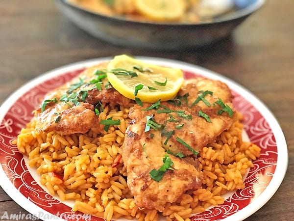 Chicken Frances cutlets served on a bed of rice and garnished with parsley.