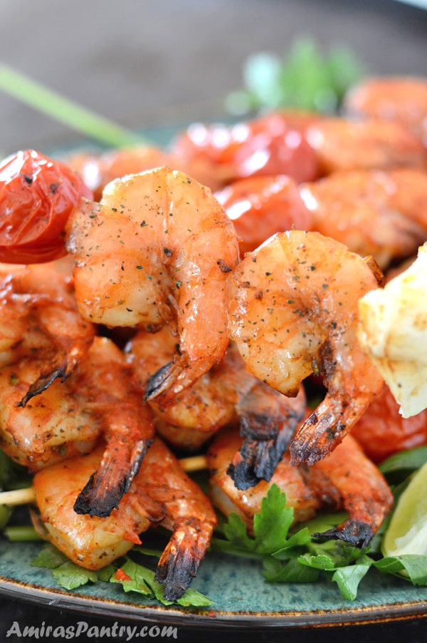 A plate of grilled shrimps on skewers with two shrimps in focus.