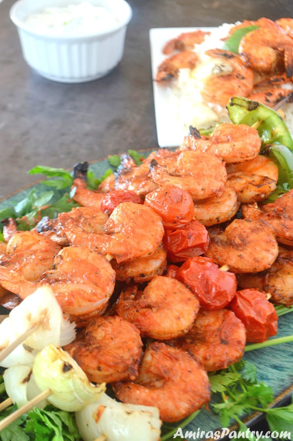 A plate full of grilled shrimp kabobs on skewers with another one on the back