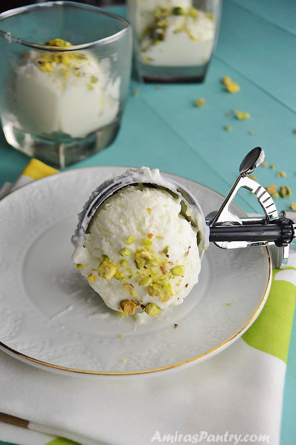 A scoop of Lebanese booza ice cream on a white plate sprinkled with pistachios