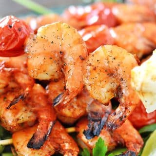 A plate of grilled shrimps on skewers with two shrimps in focus.