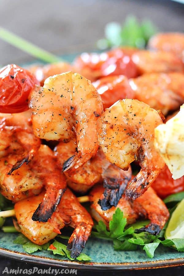 A plate of grilled shrimps on skewers with two shrimps in focus.
