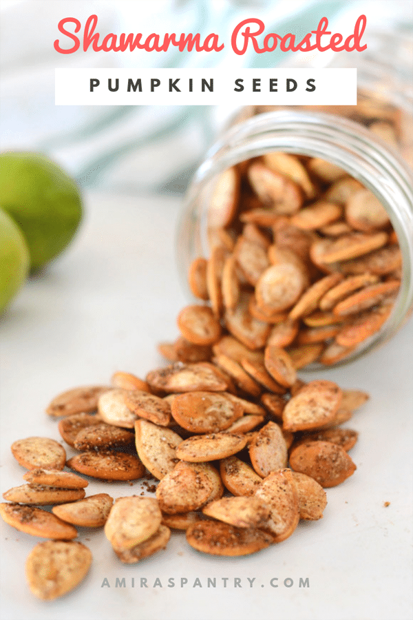 Hand holding a jar's lid filled with shawarma roasted pumpkin seeds with some fallen seeds on the back