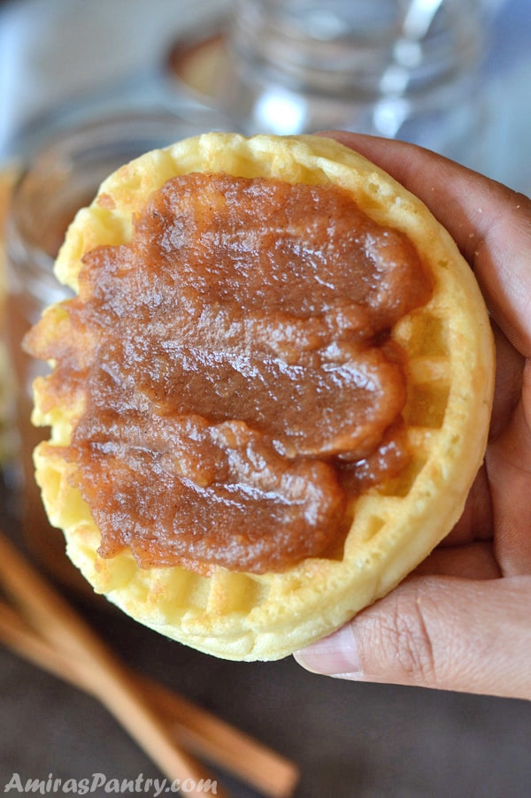 A hand holding a waffle spread with thick homemade apple butter