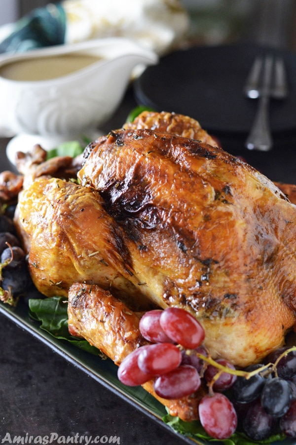 Perfectly moist turkey on a serving plate with gravy in the back