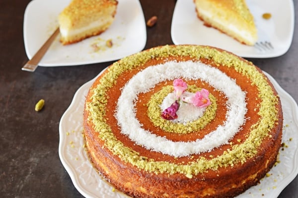 Basbousa stuffed with cream and decorated wuth ground nuts and coconut flakes with two servings on the back