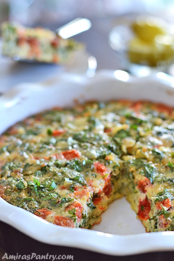 A pan of breakfast frittata with a wedge missing from it.