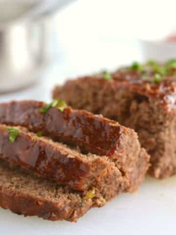 A close up look at a sliced meatloaf placed on a white plate.