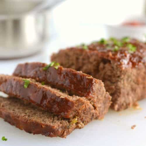 A close up look at a sliced meatloaf placed on a white plate.