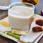 A cup of healthy date shake with some dates on a white and green napkin