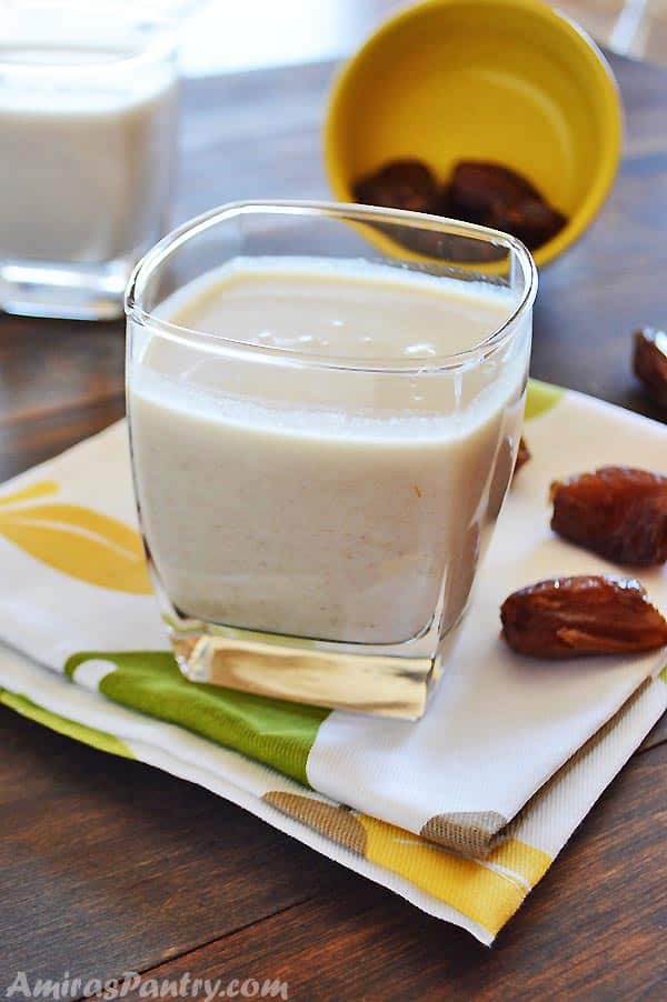 A cup of healthy date shake with some dates on a white and green napkin