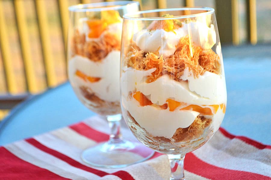 A close up of two glass cups filled with Knafeh and cream