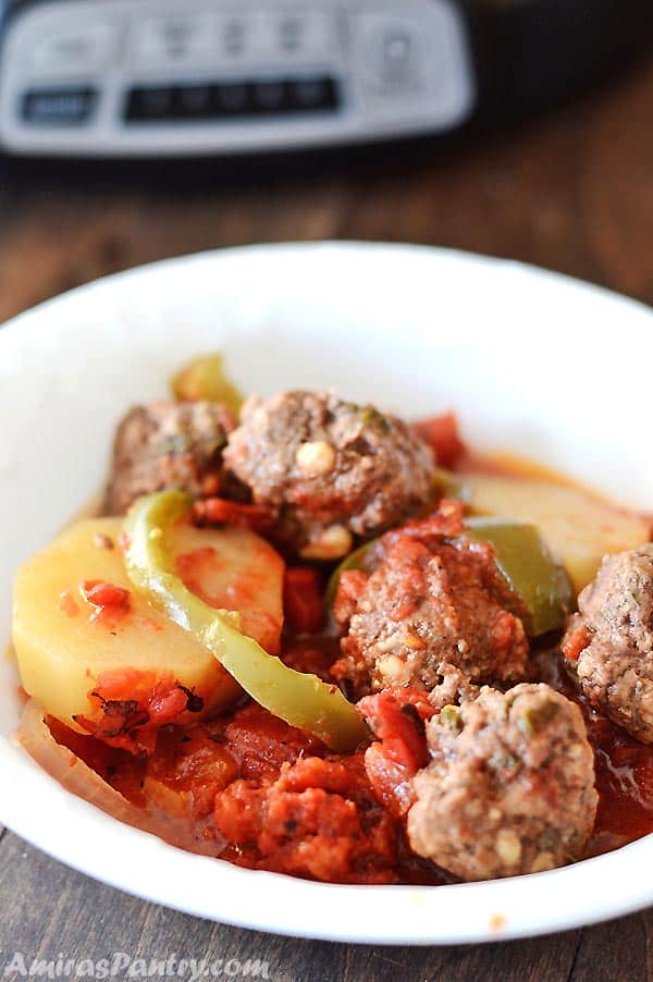 meatballs with potato and green bell pepper in a white plate.