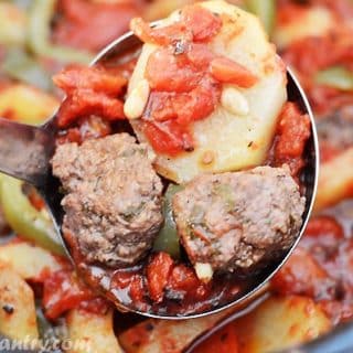 A ladle scooping some meatballs and potato from the crockpot.