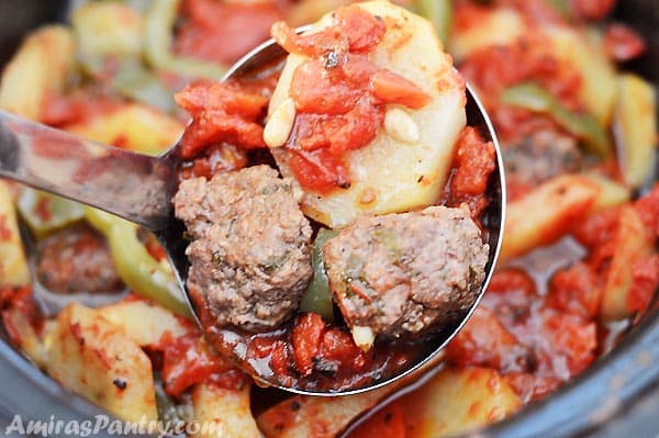 A ladle scooping some meatballs and potato from the crockpot.