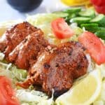 Chicken Shawarma on a bed of lettuce with cucumber, tomato and lemon wedges on the side
