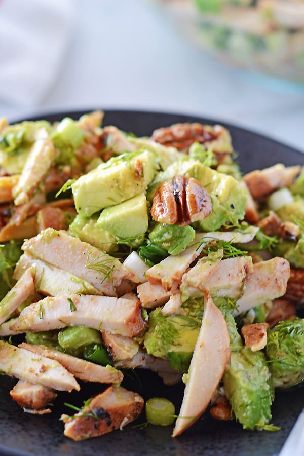 A black plate with avocado chicken salad.