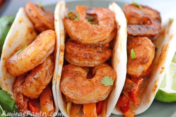 shrimp fajitas served in tortilaas and sprinkled with fresh cilantro.