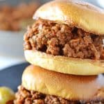 two sloppy joes sujuk sandwiches on top of eachother on a black plate