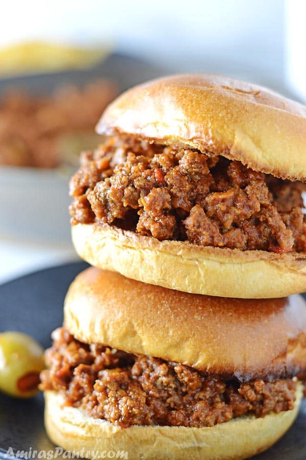 two sloppy joes sujuk sandwiches on top of eachother on a black plate