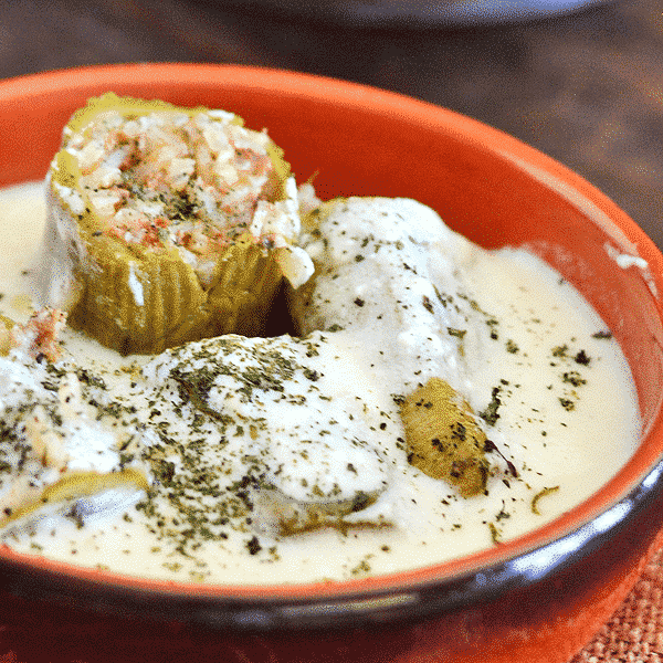 A bowl of food on a plate, with zucchini and Yogurt