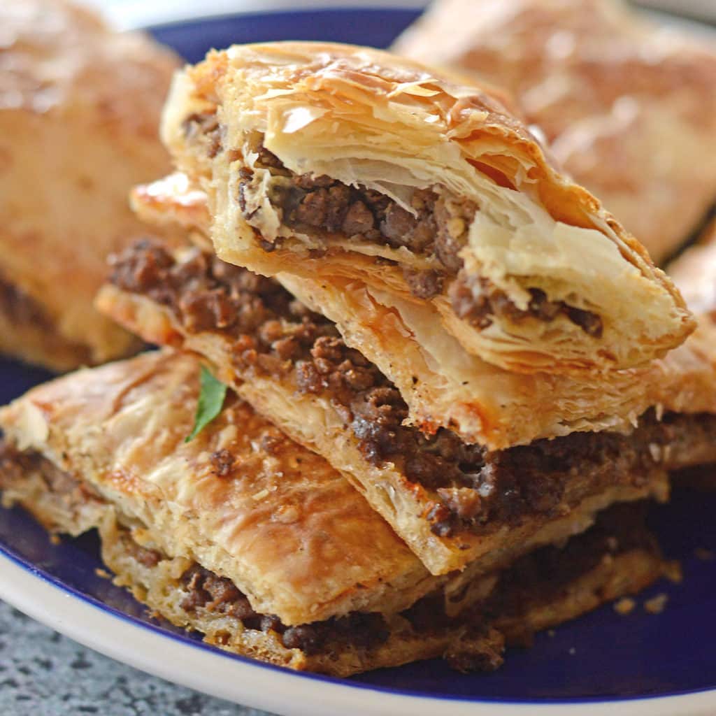 A close up of a phyllo pie on a plate, stuffed with ground beef