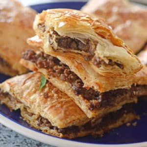 A close up of a phyllo pie on a plate, stuffed with ground beef