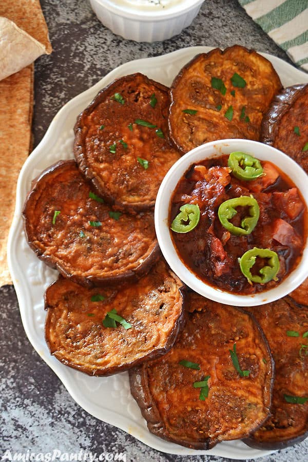 Roasted eggplant slices on a white tplate with some sauce in the middle.