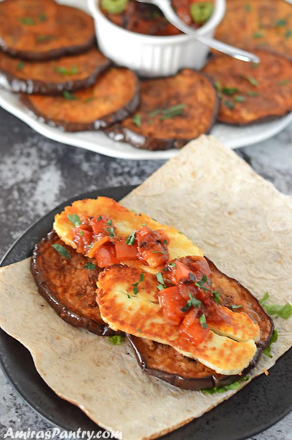 roasted eggplat slices on pita bread with Halloumi cheese and tomato relish on top.