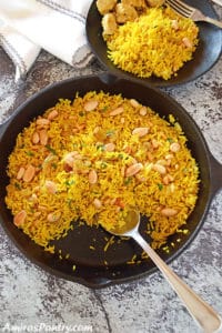 A pan of food on a table, with yellow rice and nuts