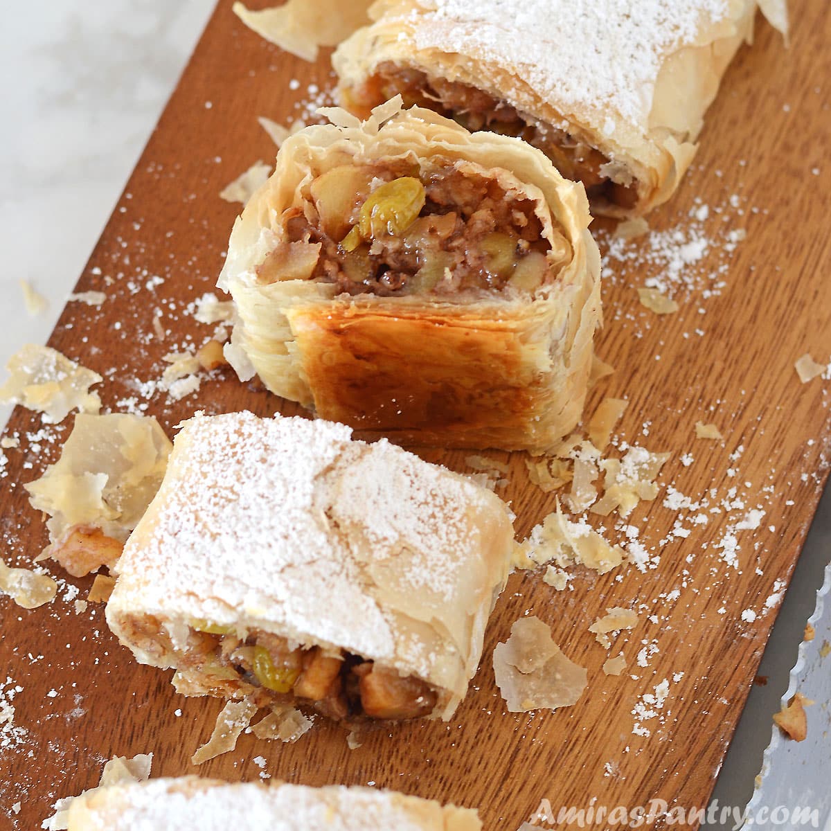 Apple strudel pieces on a wooden board with one facing up.