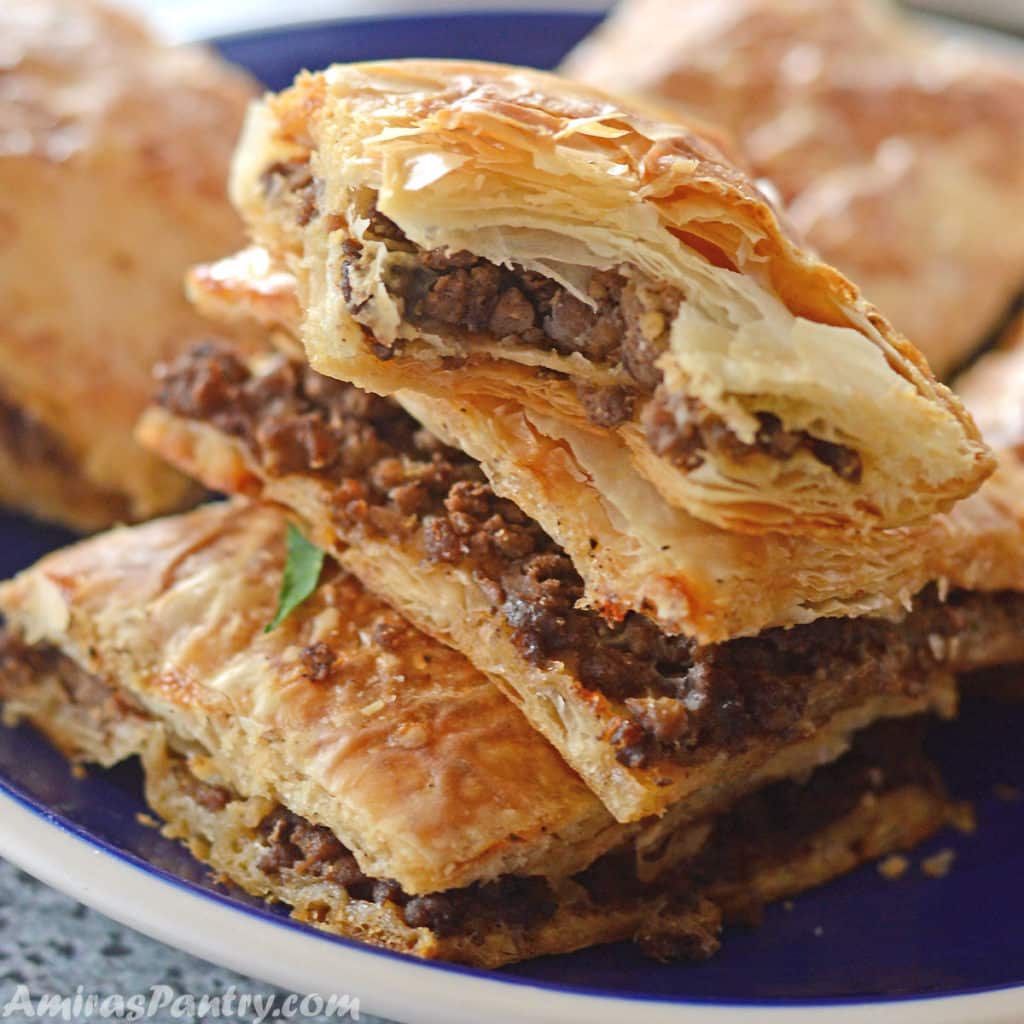Phyllo squares cut and stacked on top of eachother on a blue plate with a white rim.