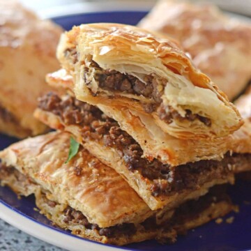 A close up of a phyllo pie on a plate, stuffed with ground beef