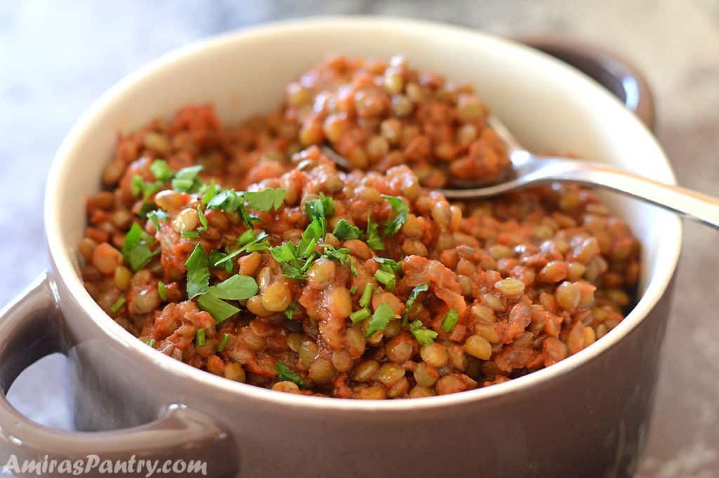 brown lentil stew in a brown bowl garnished with parsley