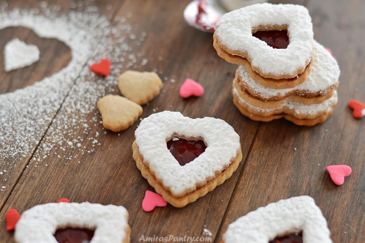 Cinnamon cookies stacked on top of each other with some heart candies on the table.