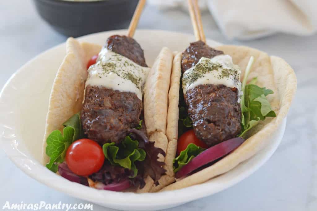 two kofta skewers in pita wraps wih greens and tomato.