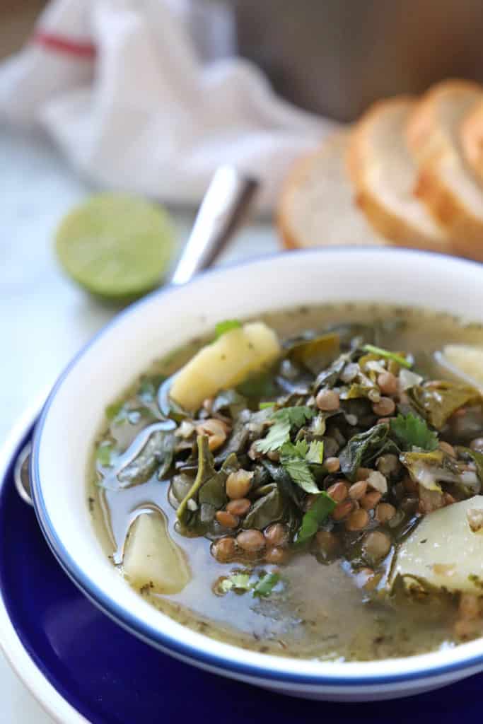 A bowl of food on a plate, with Lentil and Soup