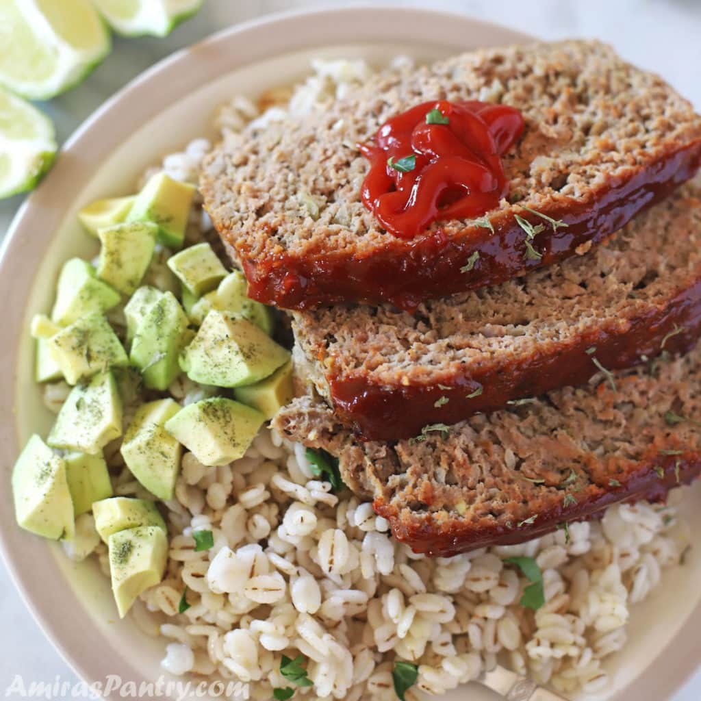 turkey meatloaf slices on a plate with cooked barley and diced avocado