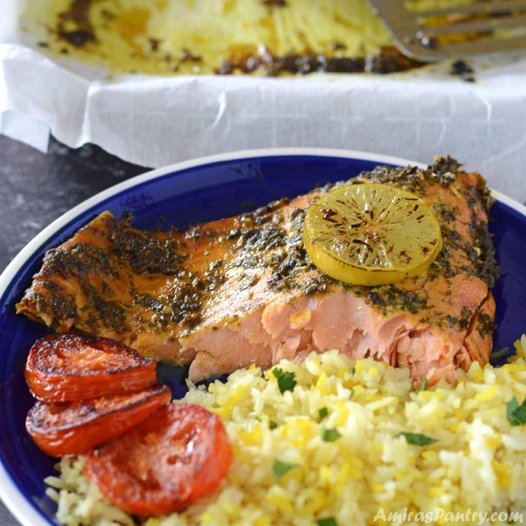 a piece of baked salmon with yellow rice on a blue plate