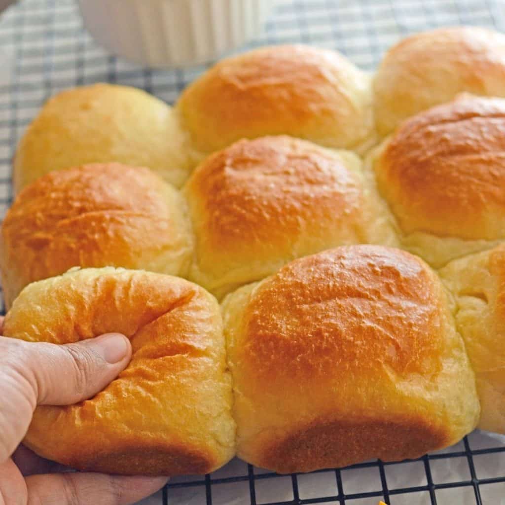 A hand pulling a piece of bread from bread stack.