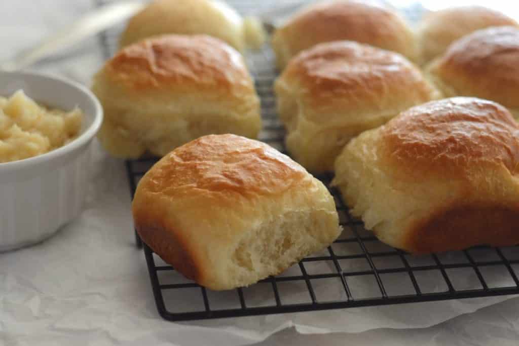 rolls on a cooling rack with a small bowl of honey butter