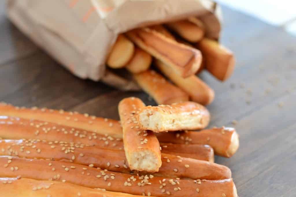 grissini breadsticks on a wooden table with a brown bag on the back full of breadsticks