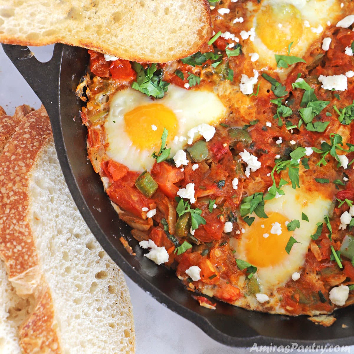 A cast iron with eggs poached in tomato sauce and feta crumbled on top.