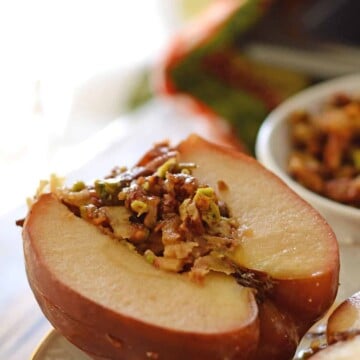 Apples stuffed with nuts and placed on a white plate.