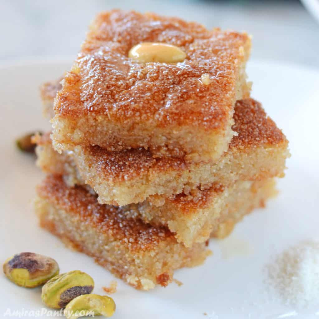 basbousa squares stacked on top of each other on a white plate