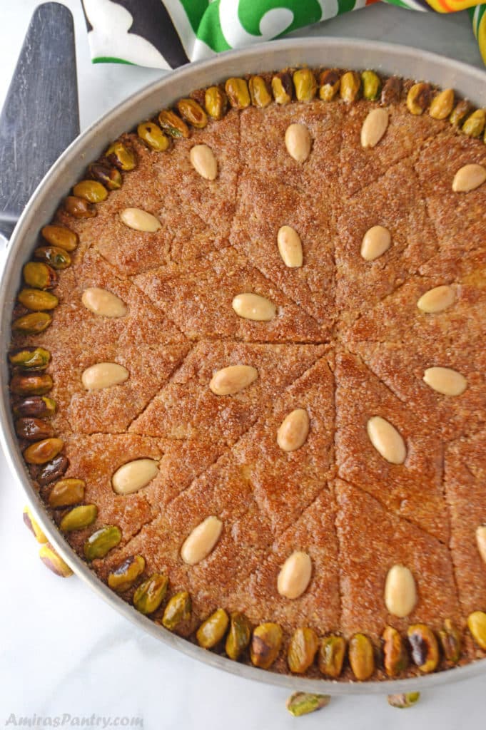 A whole tray of Egyptian basboosa garnished with pistachios and almonds.